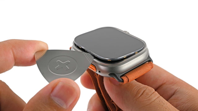 An iFixit opening pick separating the Apple Watch Ultra 4 display from its case.