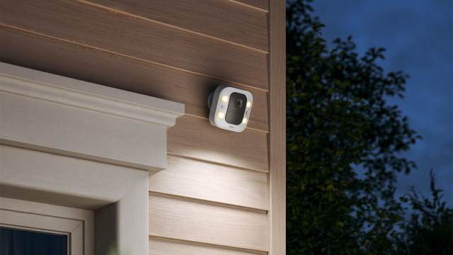 Blink Spotlight Cam 2K+ mounted outside a garage with its lights on