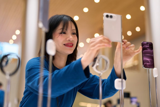 An Apple team member adjusts a star white iPhone Duo on display.