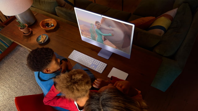Family watching a movie on a purple M4 iMac in Apple's lifestyle photograph.