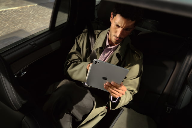 Person holding an iPad Pro while sitting beside a window